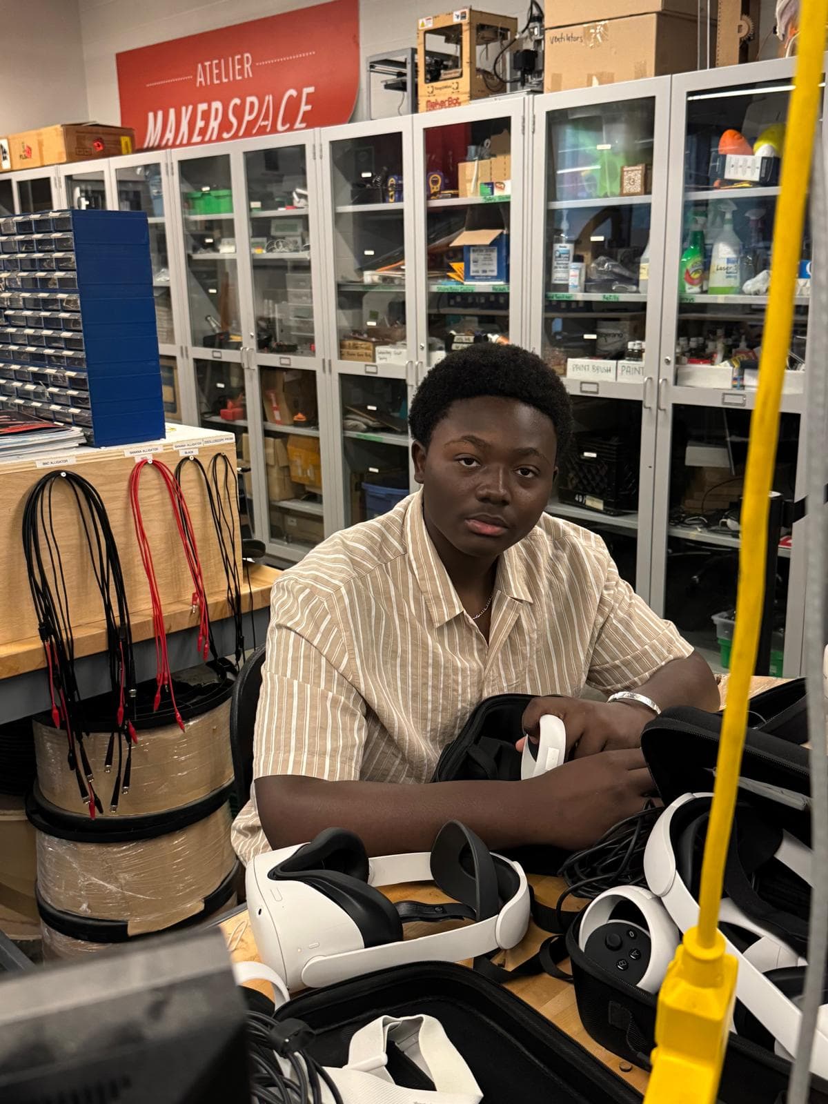Rayann working in a makerspace surrounded by electronics equipment.